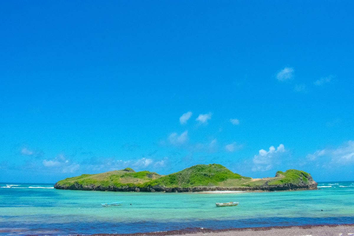 Green island surrounded by turquoise water and small fishing boats, Malindi coast Kenya