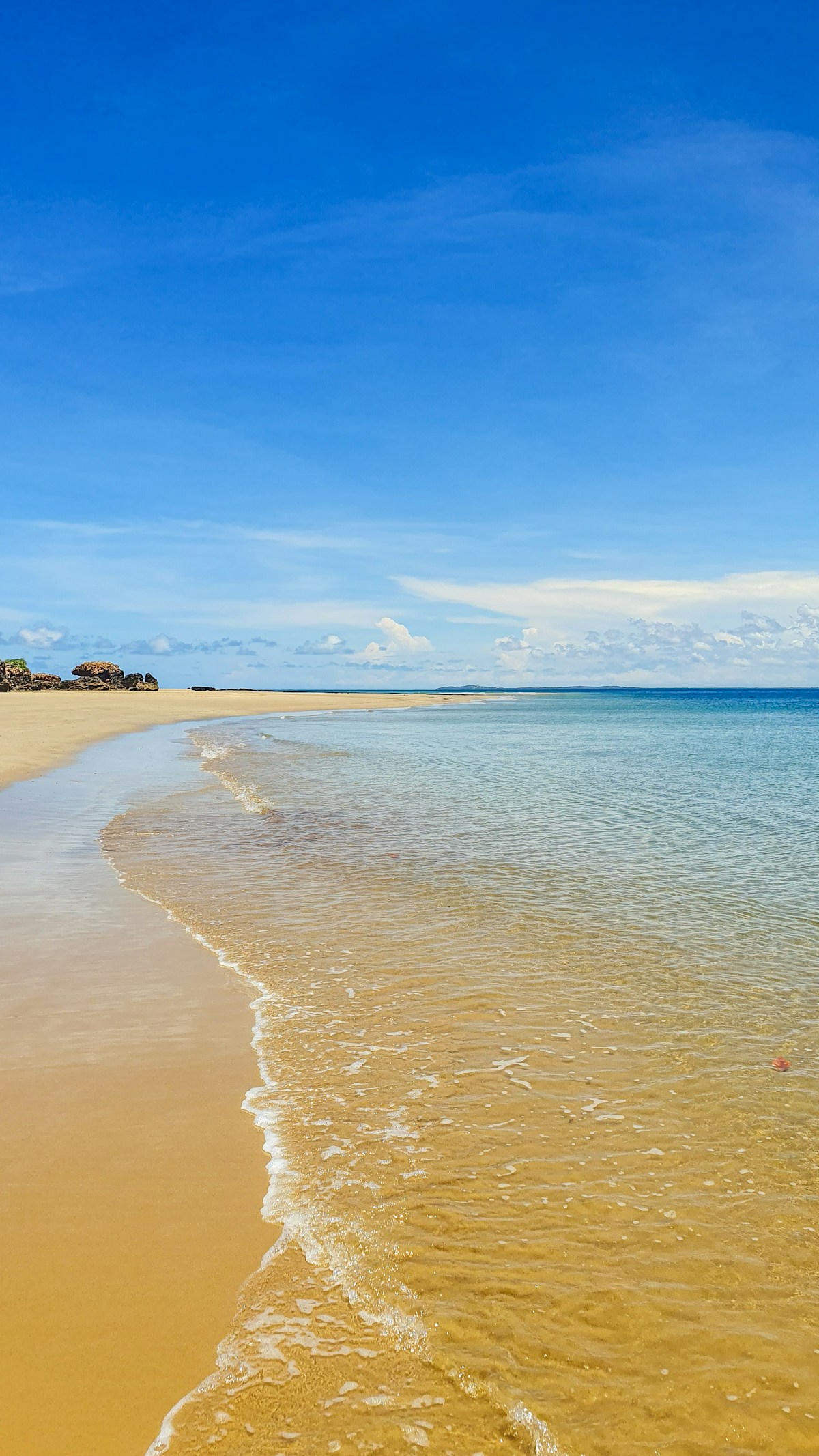 Empty sandy beach with turquoise water under blue sky, Lamu Island Kenya