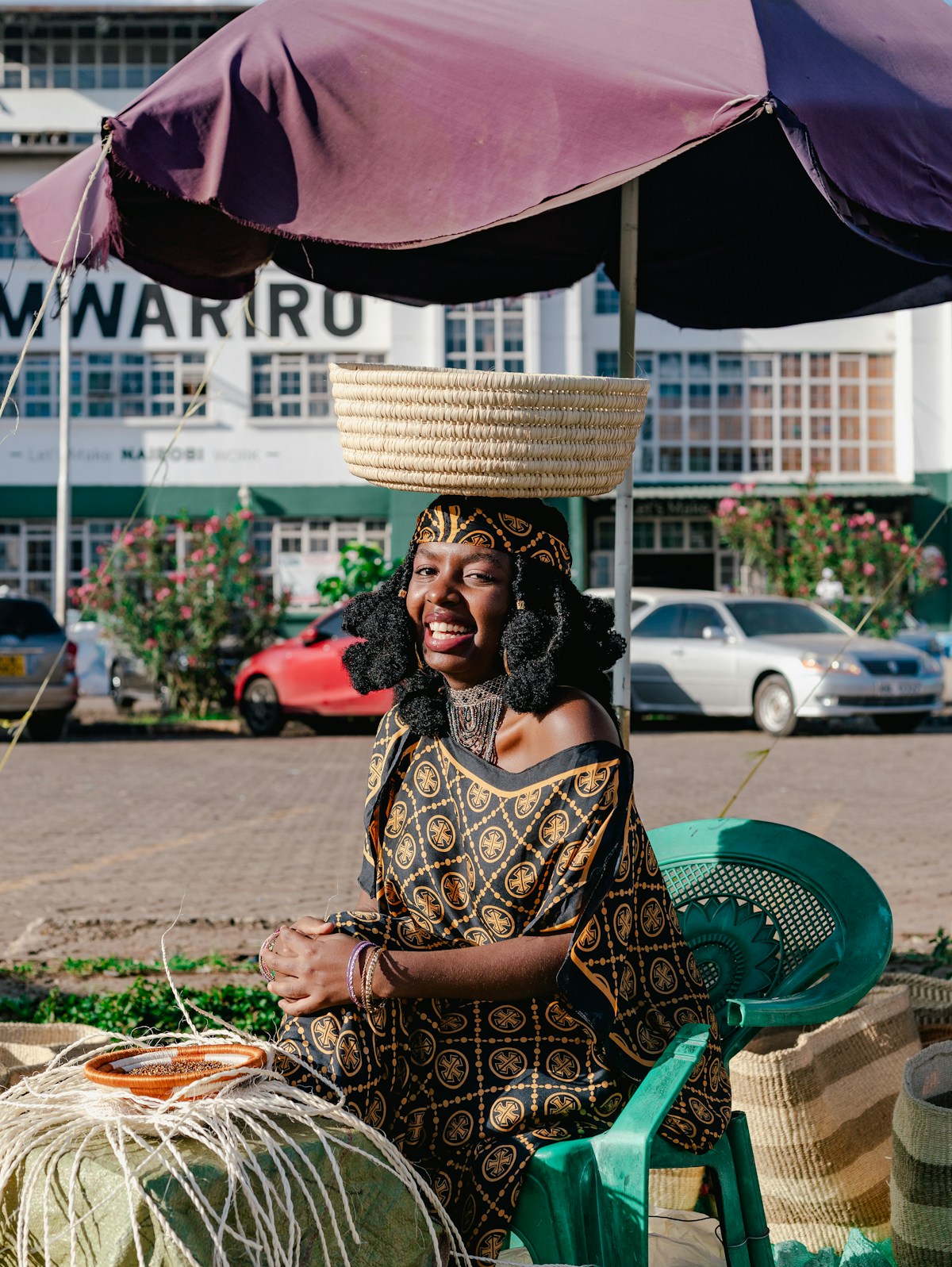 Kenyan woman in traditional dress with basket on her head at a Nairobi market