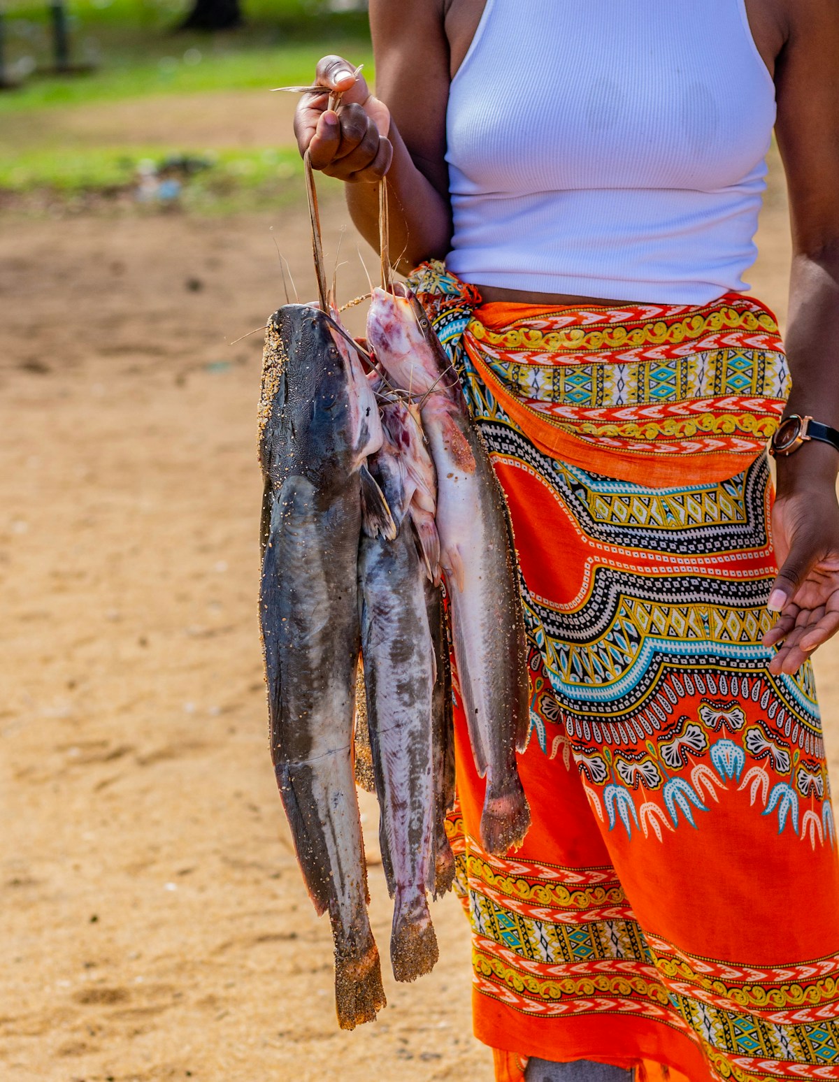 Woman holding freshly caught fish at the lake shore, East Africa