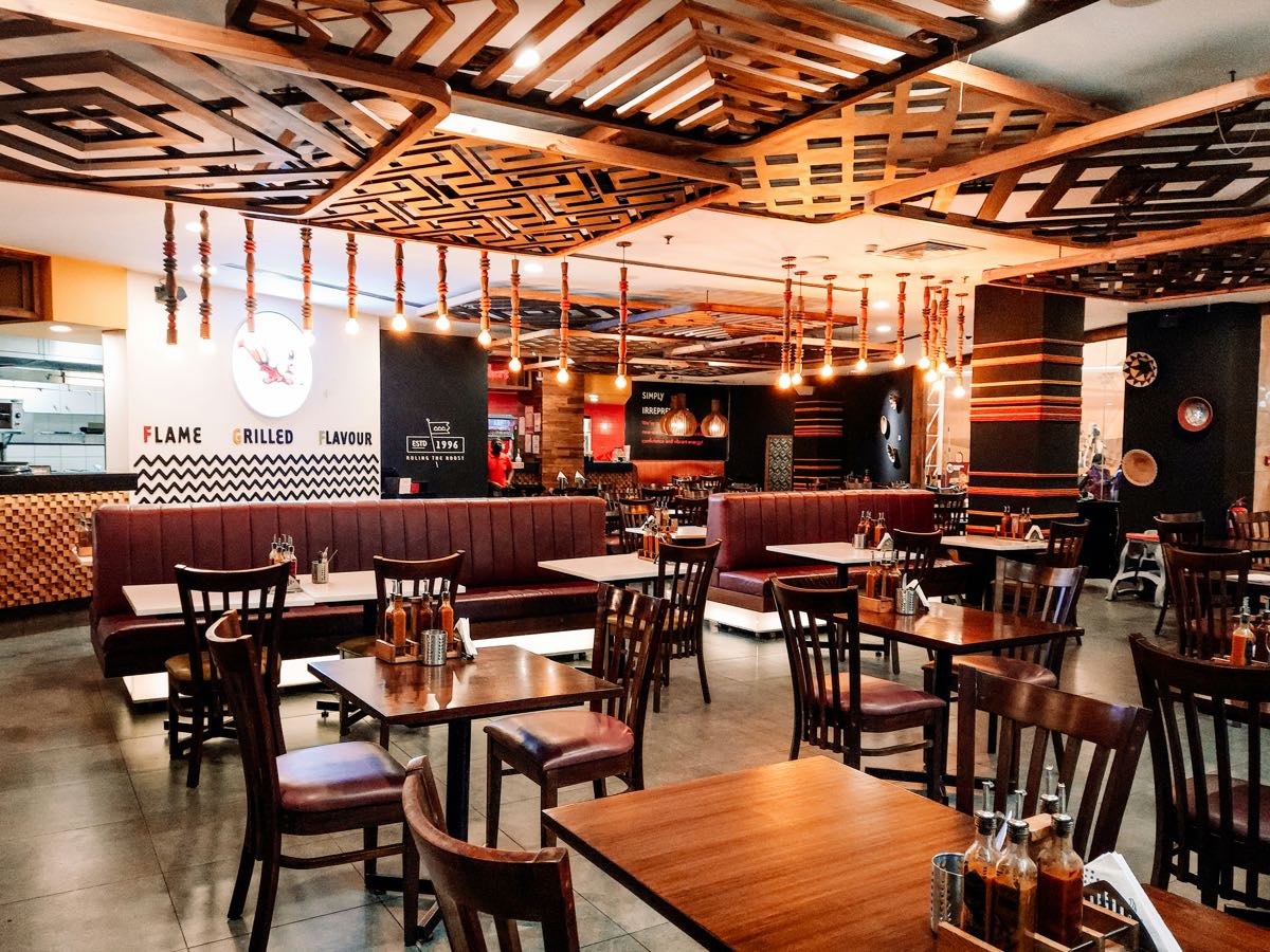 Modern restaurant interior with warm wood tones and 'Flame Grilled Flavour' signage