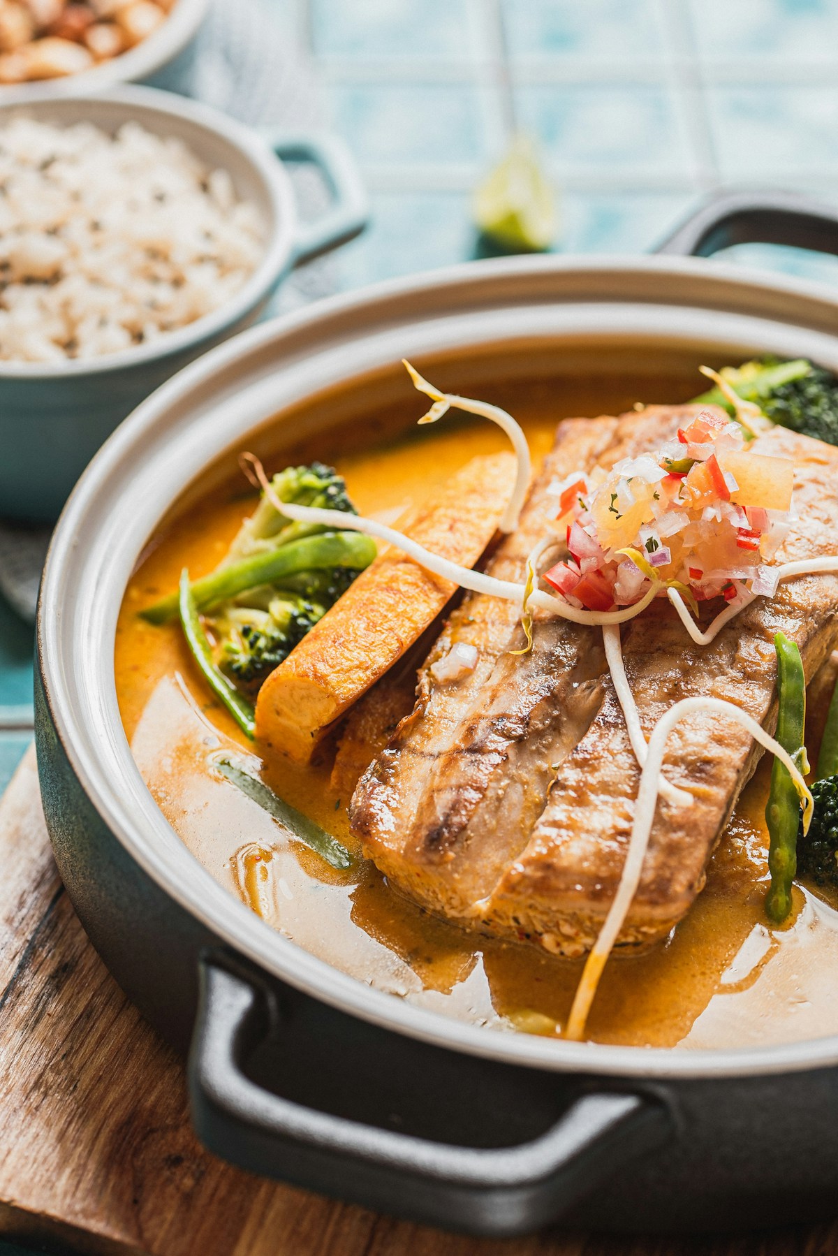 A fish fillet in golden coconut curry sauce served in a black pot, representing Mombasa coastal Swahili cuisine