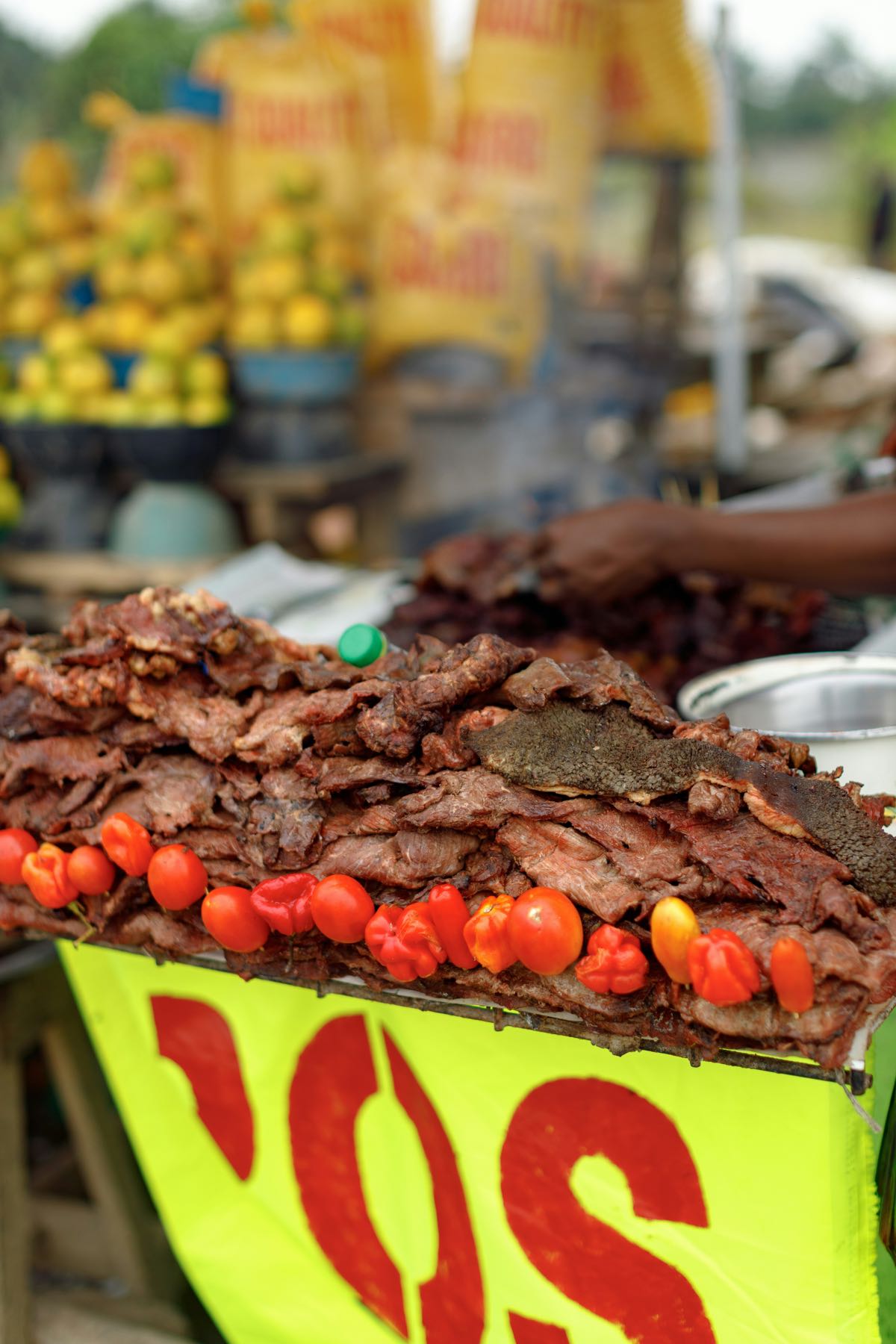 Smoked and grilled meat piled high at a street food stall with fresh chillies
