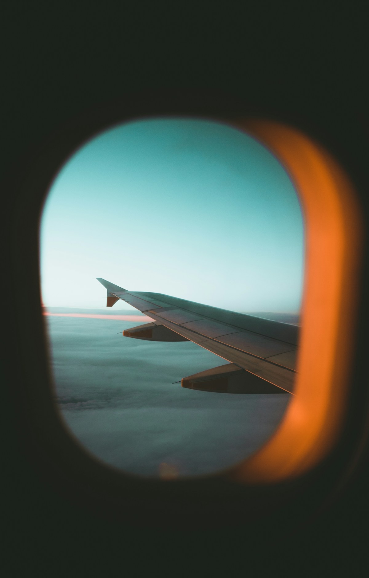 View of an airplane wing through the cabin window above the clouds
