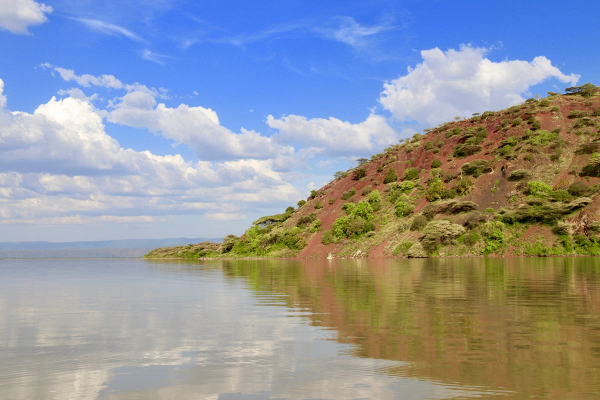 Red volcanic hillside rising above Lake Baringo, Kenya Rift Valley