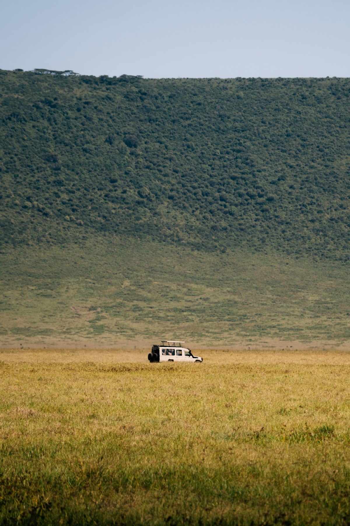 Safari vehicle driving across open savanna grasslands on a game drive in Kenya